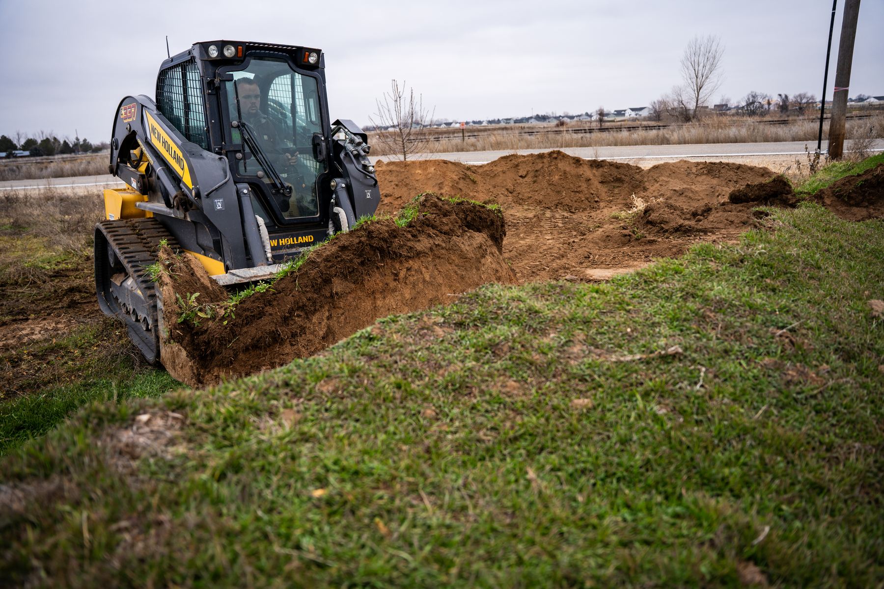 Compact track loader grading a drainage swale.